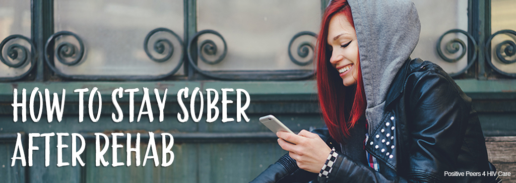 Picture of a red-headed girl wearing a hoodie and smiling while looking at her phone. Image says, "How to Stay Sober After Rehab"