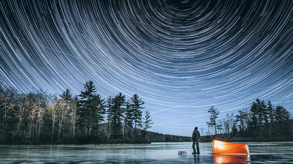 Man staring up at large sky with falling stars, contemplating life.